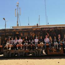 Students lined up and sitting in the back of a truck in the desert