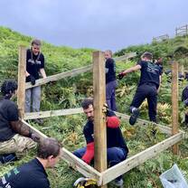 Volunteers creating a wooden support for tree planting