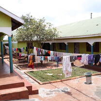 The patio of the orphanage. Some laundry, two porches, three small meadows, a tree.