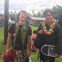 Two male students wearing backpacks and leis