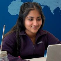 young female teacher smiling at computer virtual world behind her