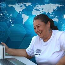older female teacher smiling at computer with virtual world behind her