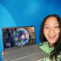 young female teacher holding up laptop with a big smile