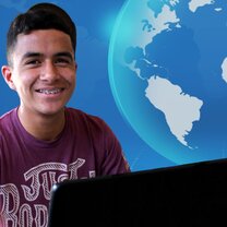 young male smiling at computer desk with virtual world in background
