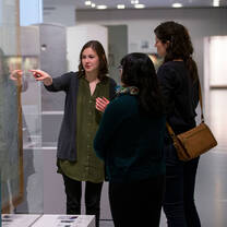 A student points to something on a map as two women watch