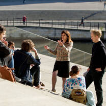 A professor lectures a class of students who are seated on concrete steps
