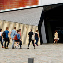 A group of students walks into a geometric-shaped building