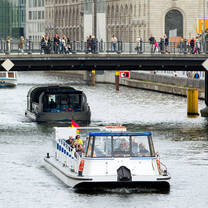 A boat floats down the river with a bridge overhead