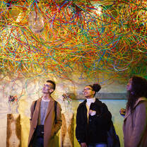 Students stand underneath colorful artwork