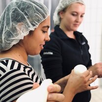 two women with hairnets on making cheese