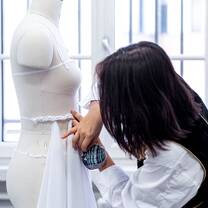 A student pins fabric onto a mannequin during a class at Accademia del Lusso Milan
