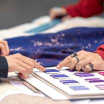 Students pointing at a colour palette with blue and purple shades and blue fabric