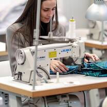 A student uses a sewing machine to create a garment at Accademia del Lusso Milan