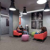 Students relaxing together on red sofas in a shared area of Accademia del Lusso school of fashion