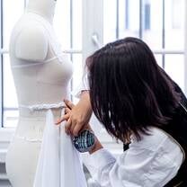 A student pins fabric onto a mannequin during a class at Accademia del Lusso Milan
