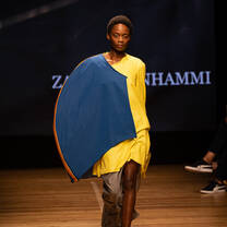 A model walking down the catwalk towards the camera displaying fashion student creations from Accademia del Lusso Milan