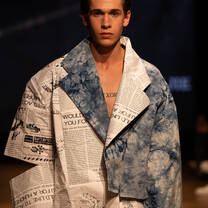 A model walking towards the camera displaying a student creation with blue and white newspaper print garments