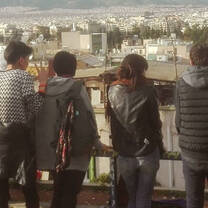 A group of students lined up a long a fence look at the view before them in Athens, Greece