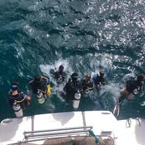 Group of teens in scuba gear entering water from boat