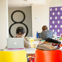 A student seated at a table looks at their laptop.
