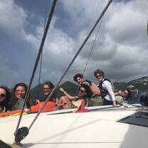 Group of teens smile at camera from deck of sailboat