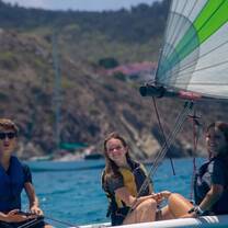 Three teenagers sailing small sailboat