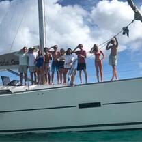 Group of teens standing on deck of monohull