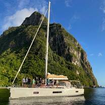 Group of teens standing on deck of monohull sailboat with island in background