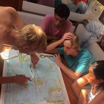 Three teens and instructor in sailboat planning passage on map