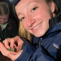 Teen girl in headlamp holding tiny frog