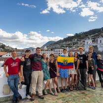Group of teens hold Ecuador's flag with Quito skyline in background