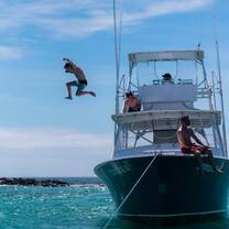 Boy jumps off boat into turqouise water