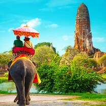 A couple riding an elephant through vibrant gardens