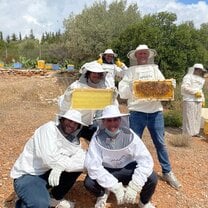 students in protective clothing showing off beekeeping