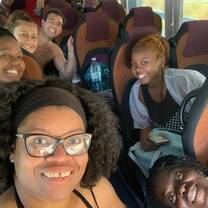 A group of adults sitting on a bus and smiling for a selfie