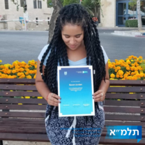 Woman with long black twists looking down at a certificate she's holding up to the camera