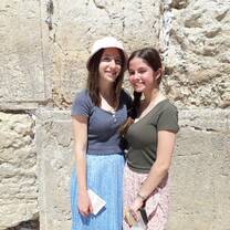 Two women stand in front of the Western Wall