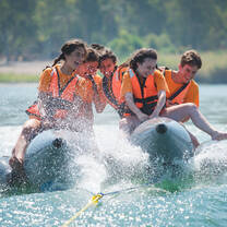 Teens banana boating on the water.