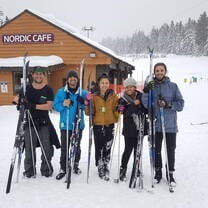 a group poses for a photo in front a of a ski lodge while skiing