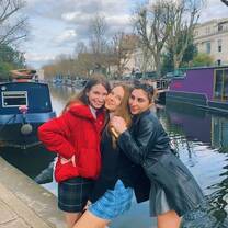 3 students hug in front of a river view