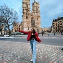 student poses in front of european architecture