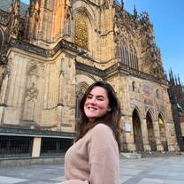 student smiles in front of castle in prague