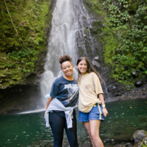 two students pose in front of a waterfall in costa rica