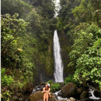 student sits in front of a waterfall