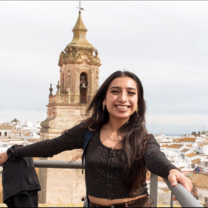 student poses in front of spanish architecture 