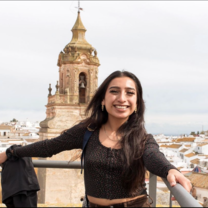 student poses in front of spanish architecture 