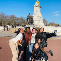 students pose in front of monument in london