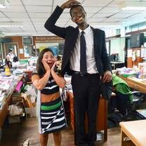 A very tall teacher stands next to a smaller Thai Teacher