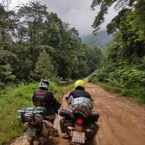 two teachers ride motorbikes down a dirt road in Isaan 