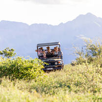 A game viewer with students and a magnificent view of the Drakensberg mountains in the background